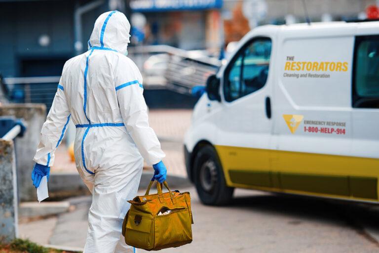 Cleaner in PPE witn equipmnet in bag going to van