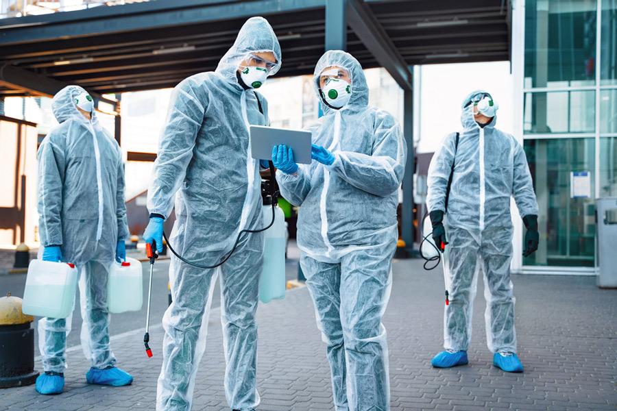 Cleaners in PPE looking at task list on tablet for mold removal